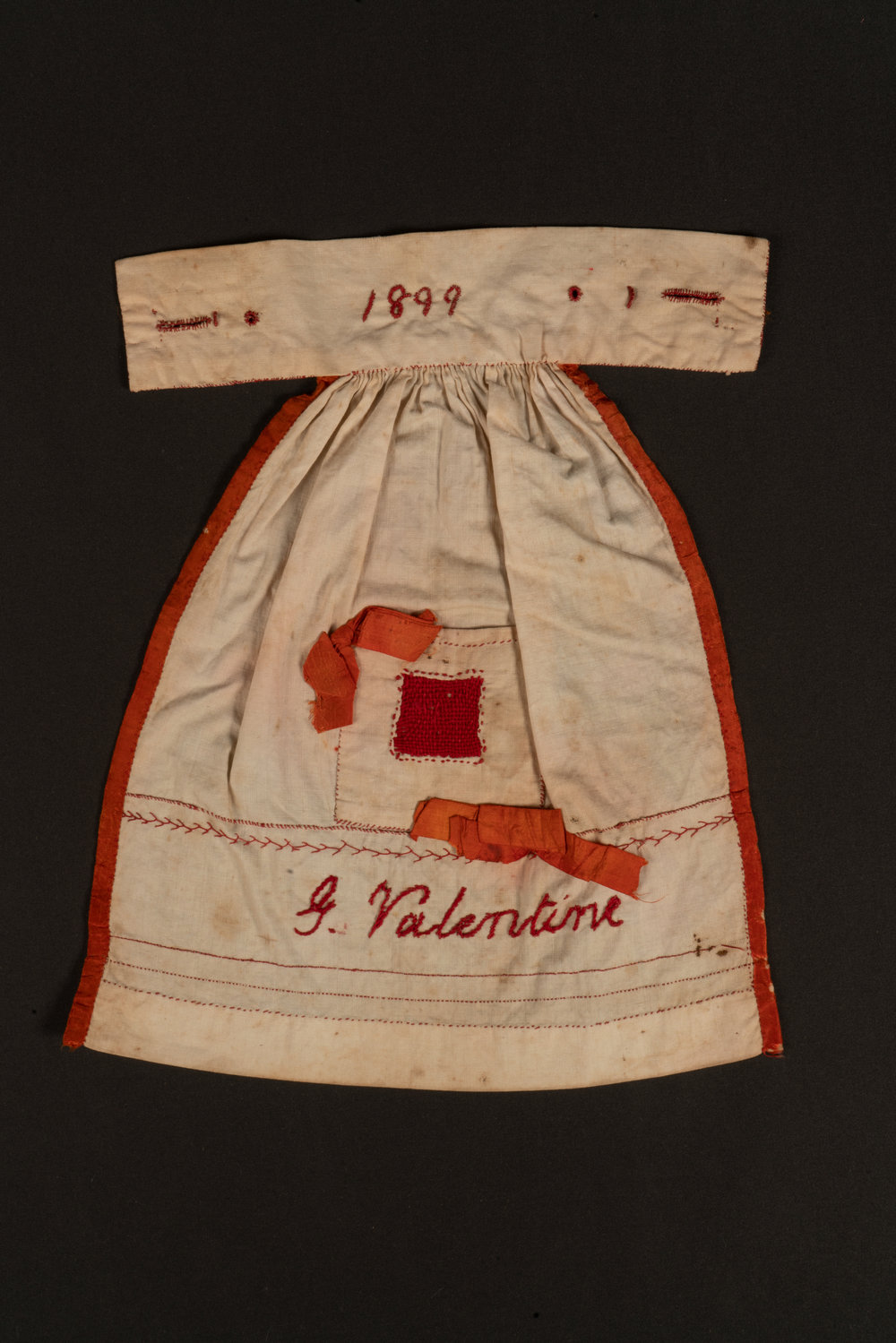 Doll's apron sampler, 1899
