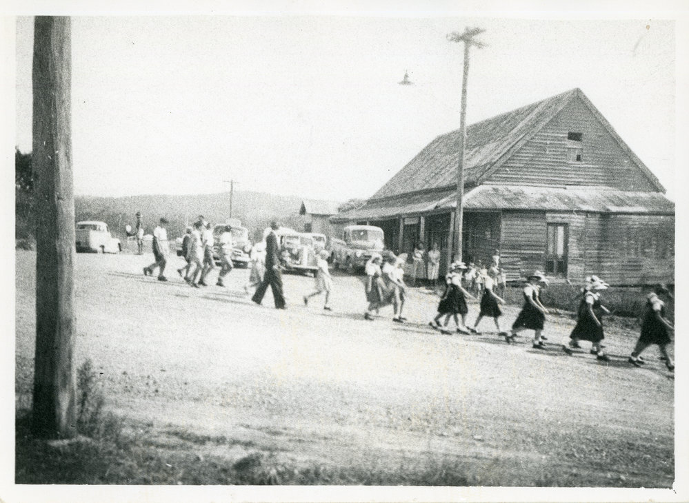 Schoolchildren file past Pullen's store, c.1938