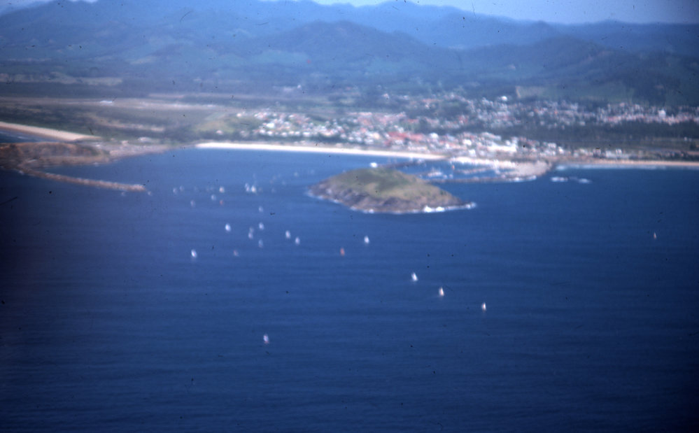 Sails of the Hobie catamarans beyond the Harbour, 1977