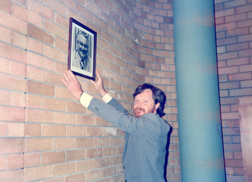 Derek Firman with his father's portrait in the Council Chamber