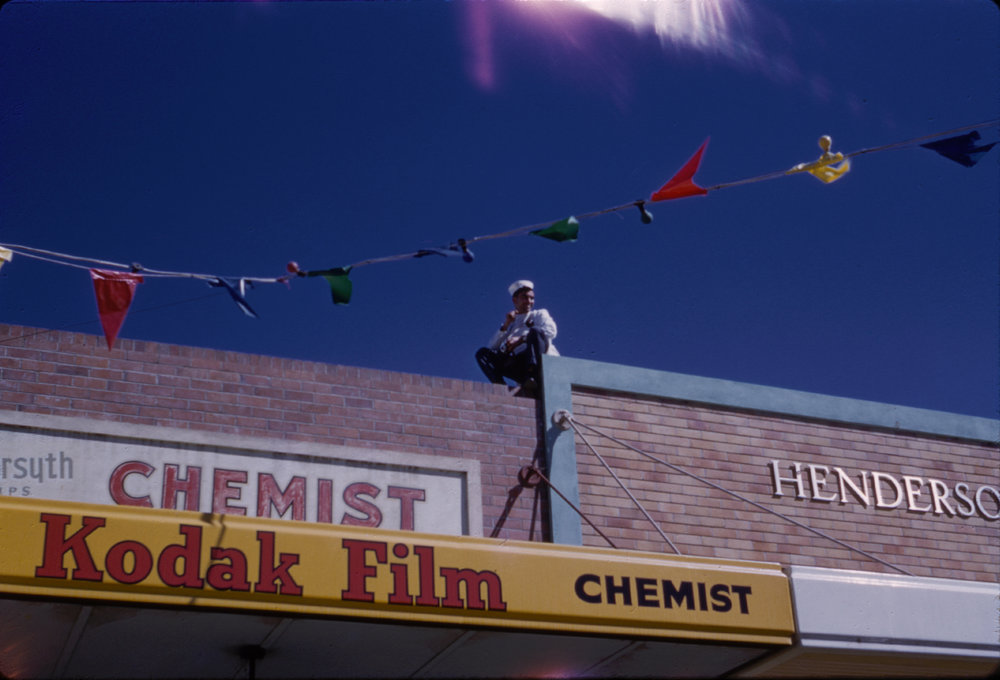 Man sitting on shop roof, c. 1960s