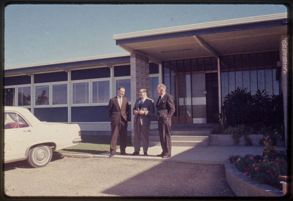Three men in front of building, c. 1966