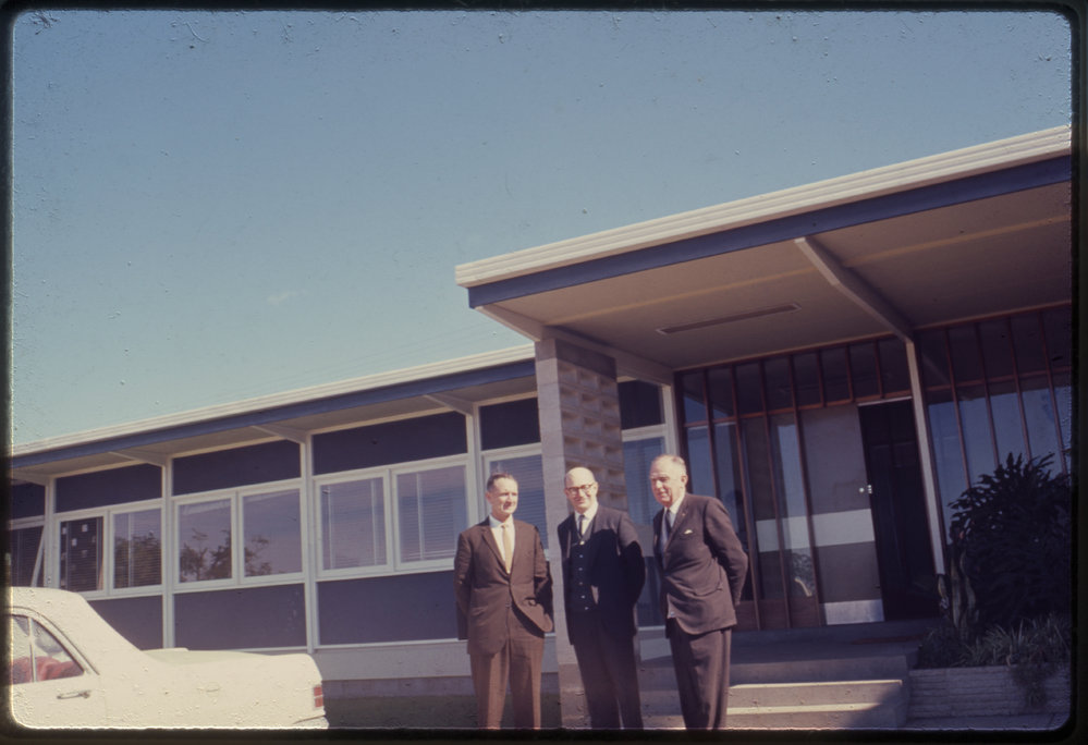 Three men in front of building, c. 1966