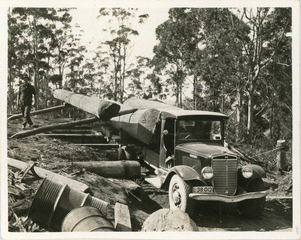 A sawyer unloads timber from an International truck, 1936
