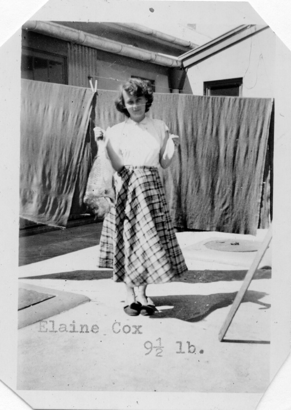 Elaine Cox outside the laundry with fish, 1952