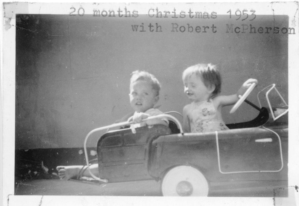 Robert McPherson and Linda Hobman riding in their pedal car, Christmas 1953