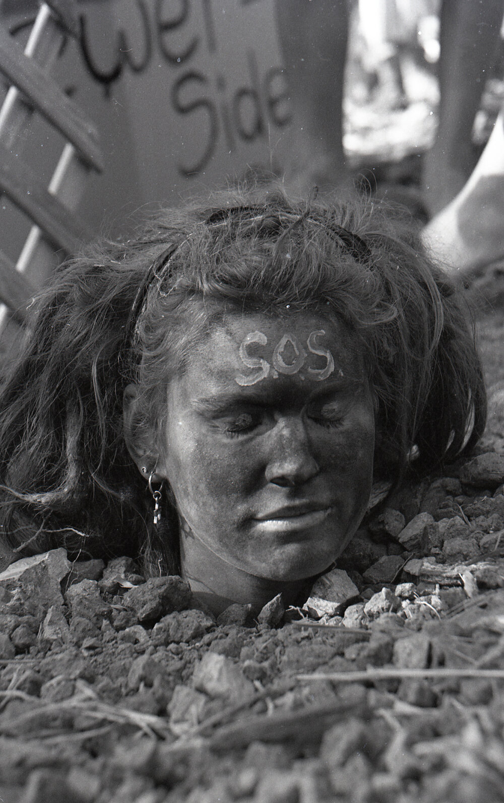 A protestor is buried up to her neck in the sand, late 1991