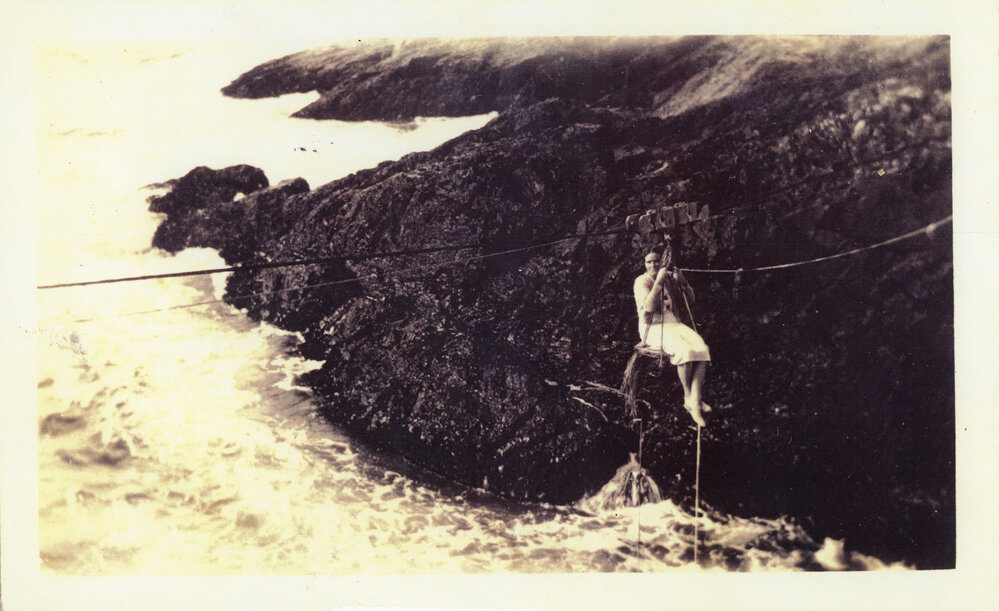 Jess Tulk swings across to Archie Island from South Solitary Island, c. 1937