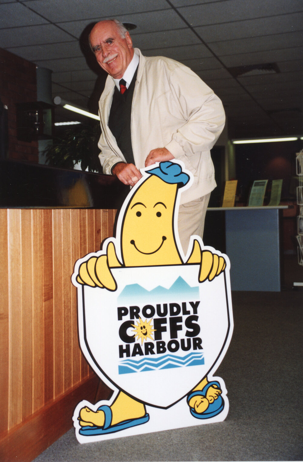 Councillor John Essex-Clark with the "Proudly Coffs Harbour" logo