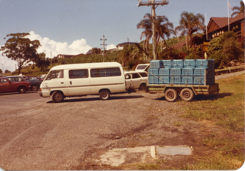 White transit van towing a trailer with crates, April 1982