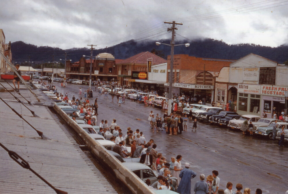 Waiting along High Street for the parade after a storm, c.1960