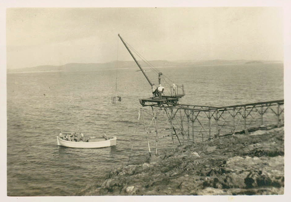 South Solitary Island jetty with crane and launch in a calm sea, 1946