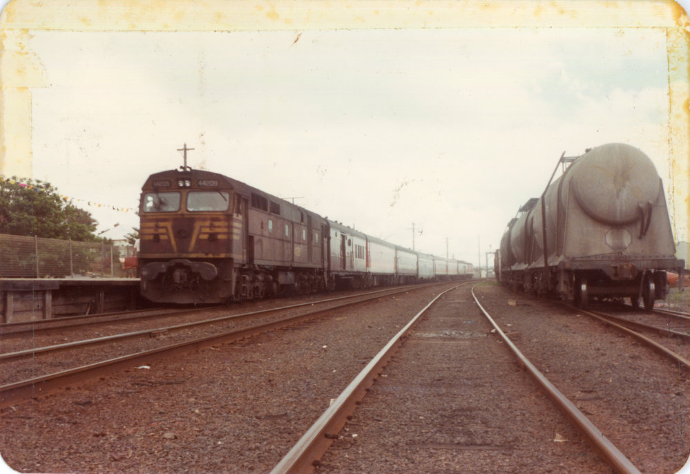 A Sydney to Brisbane passenger train beside cement wagons at Coffs Harbour Railway Station, c.1970s