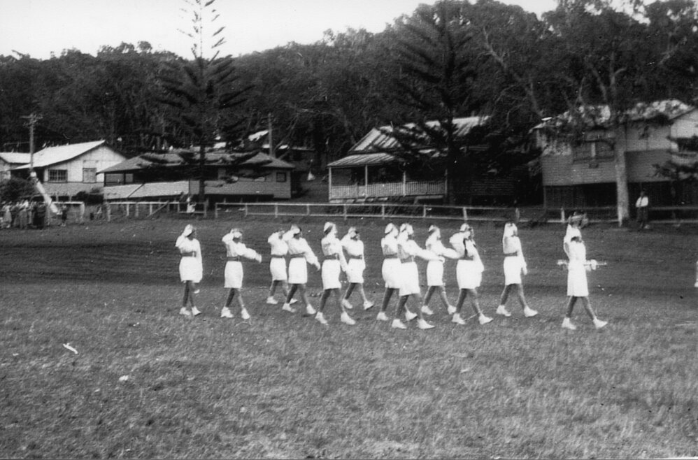 Marching girls in a district competition on the oval at Sawtell Reserve, 1960