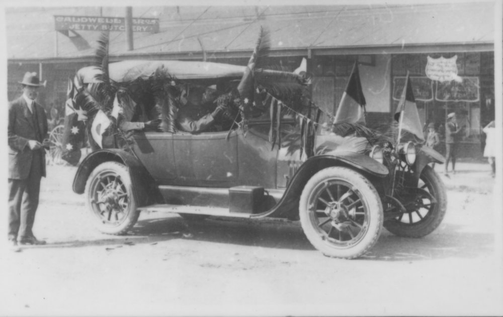 Motor car decorated with foliage and flags, 1920s
