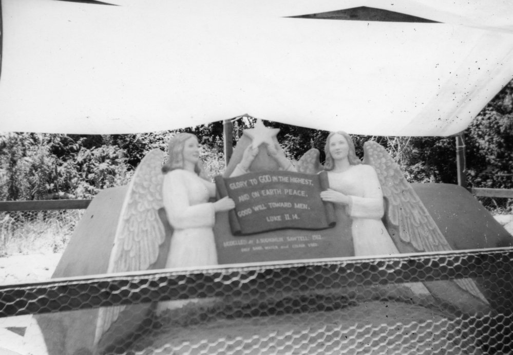 Sand sculpture of two angels holding a religious verse, 1962 