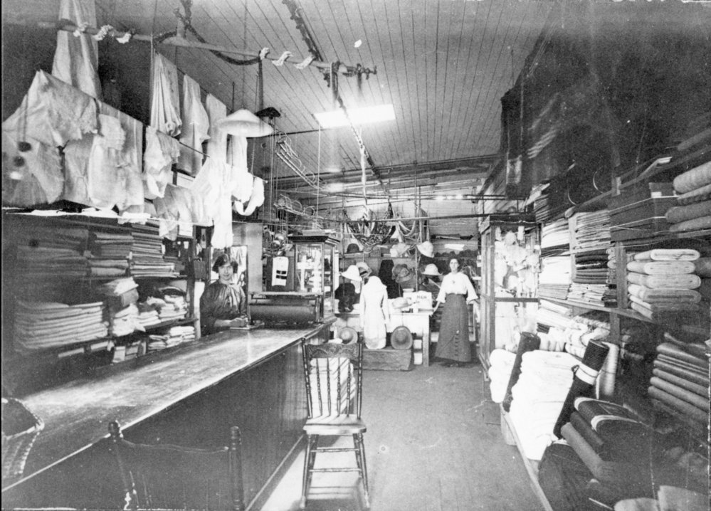 Two shop assistants standing inside Bray's General Store, c. 1910s