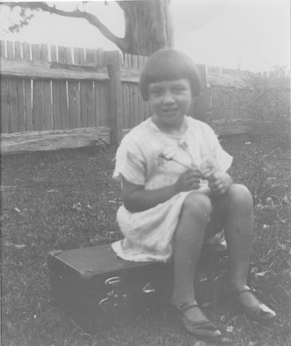 Heather McLeod sitting on her school case, c.1930