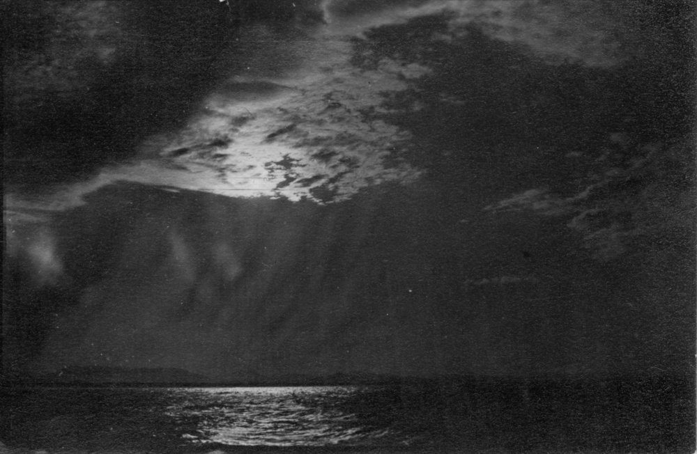 The moon behind clouds over the ocean, c.1912