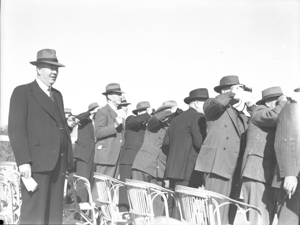 A group of men watch the races at the Coffs Harbour Racing Club's inaugural meeting, 7 August 1948