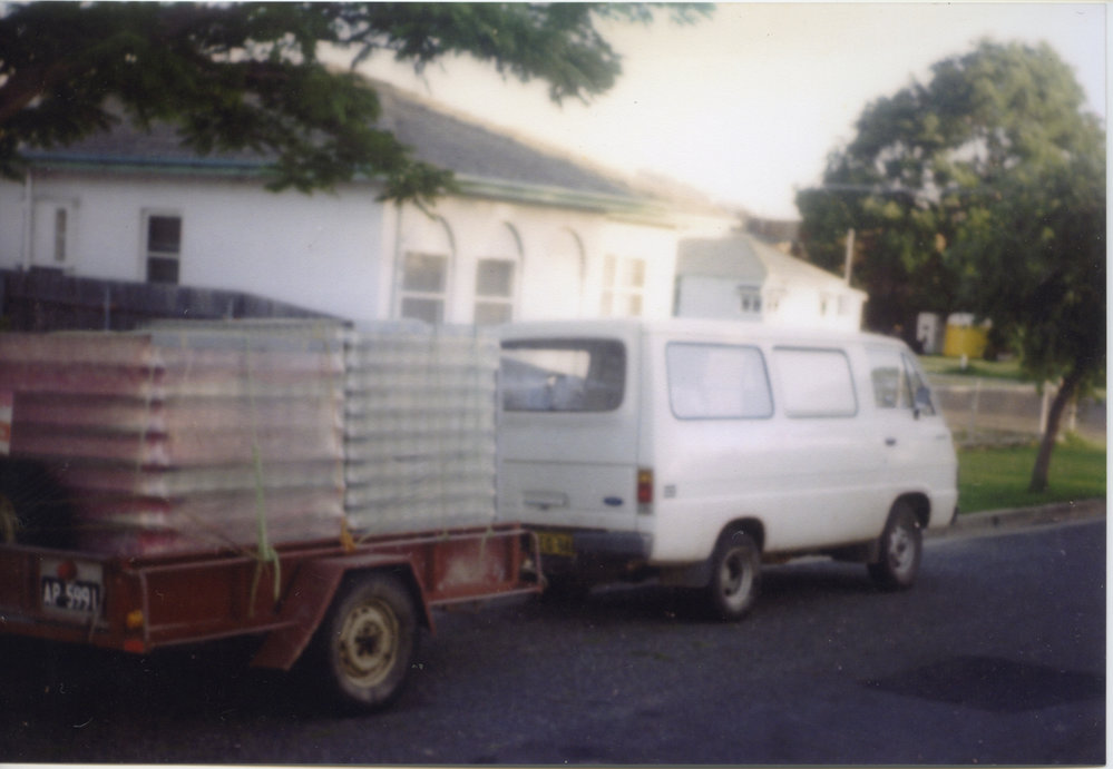 White van towing a trailer with crates, 1970s