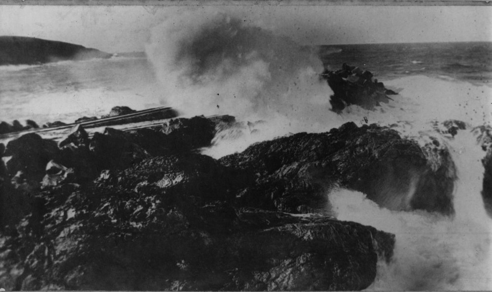 A stormy day at Jetty Beach with waves crashing over the tramline, early 1900s