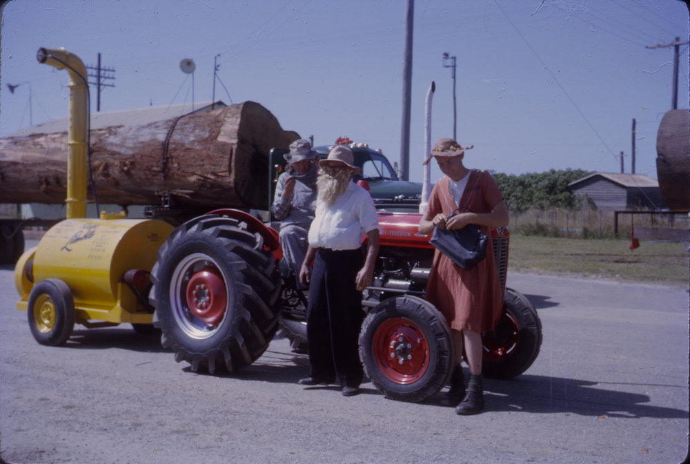 Men in costume with tractor and Limblo machine in street parade, Coffs Jetty, 1964