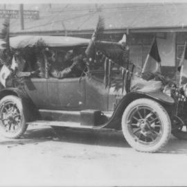 Motor car decorated with foliage and flags, 1920s