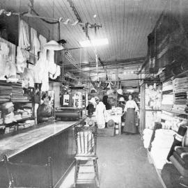Two shop assistants standing inside Bray's General Store, c. 1910s