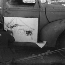 Airman Alan Munro sketches against a utility, 1941