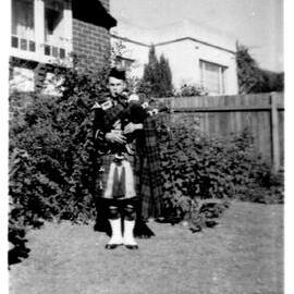 Hugh Nicol in full dress playing the bagpipes at Blaxland Road, 1959