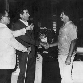 Bill Singleton and B. Bollinger presenting the Club Champion trophy 1980-1981 to Paul Worland, 1981