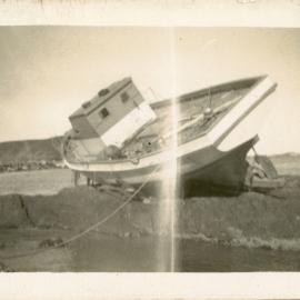 Local fisherman Syd Hardy's boat on rocks at the northern end of Jetty Beach, 24 June 1950 
