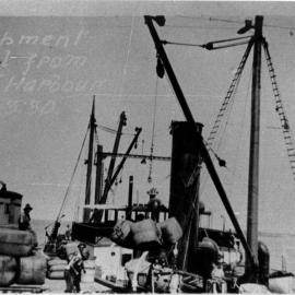 Cranes on Coffs Harbour Jetty load the first shipment of wool bales from the New England region, 5 March 1930