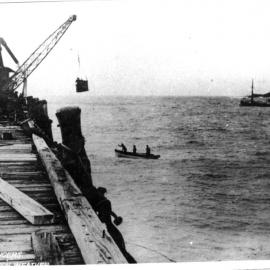 Unloading passengers in rough weather from the boat by basket to Coffs Harbour Jetty, 1908