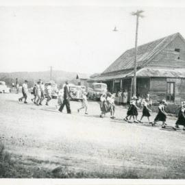 Schoolchildren file past Pullen's store, c.1938