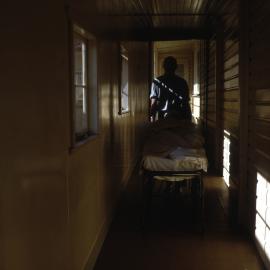Theatre corridor at Coffs Harbour District Hospital with nurse and body, September 1969