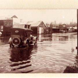 A car drives by the corner of West High Street and Lyster Street in flood waters, c. 1922 