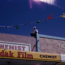 Man sitting on shop roof, c. 1960s