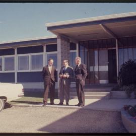 Three men in front of building, c. 1966