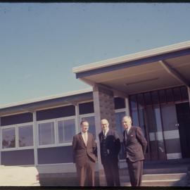 Three men in front of building, c. 1966
