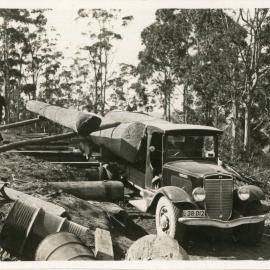 A sawyer unloads timber from an International truck, 1936