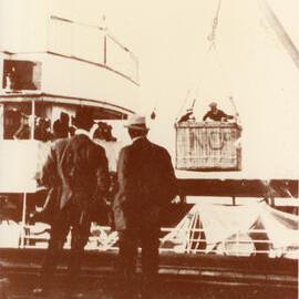 Passengers landing via a basket attached to a crane at the end of the Jetty, 1920s