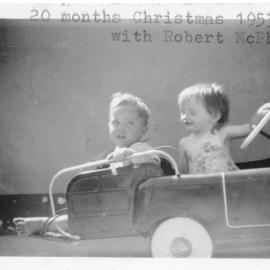 Robert McPherson and Linda Hobman riding in their pedal car, Christmas 1953
