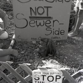 A protestor is buried up to her neck, late 1991