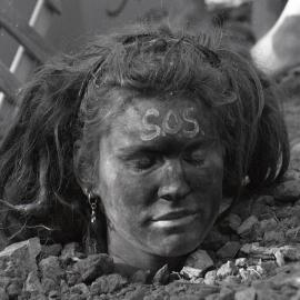A protestor is buried up to her neck in the sand, late 1991