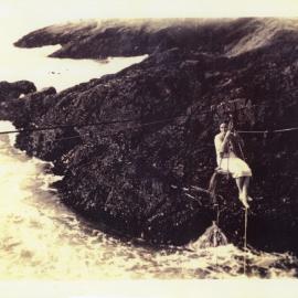 Jess Tulk swings across to Archie Island from South Solitary Island, c. 1937