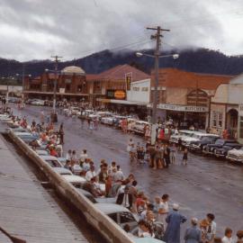 Waiting along High Street for the parade after a storm, c.1960