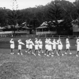 Marching girls in a district competition on the oval at Sawtell Reserve, 1960