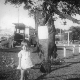 Kim Shephard with a black cod caught by Jim Worland, 1963